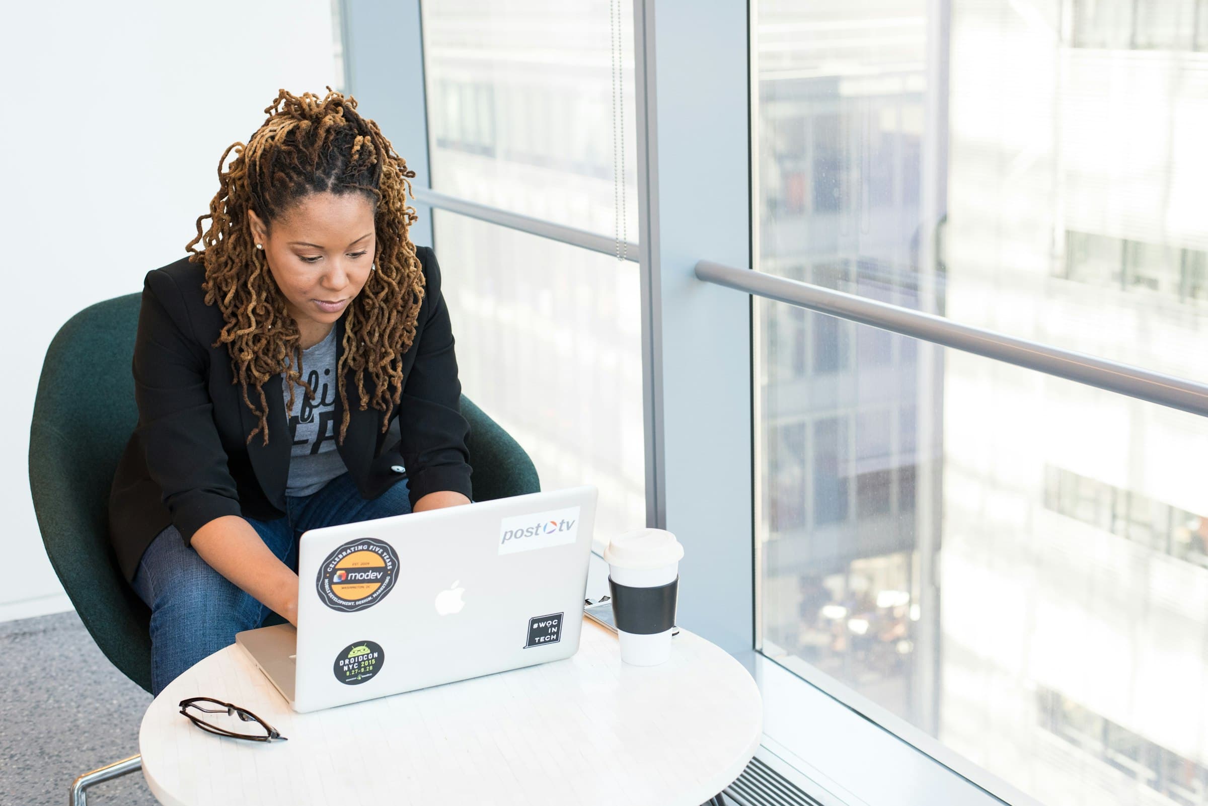 A credit analyst working through a file on a laptop by a glass window